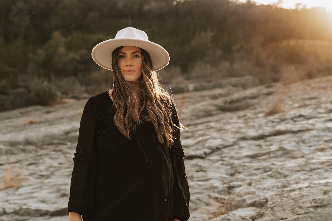 Mother in white hat at golden hour on the rocks